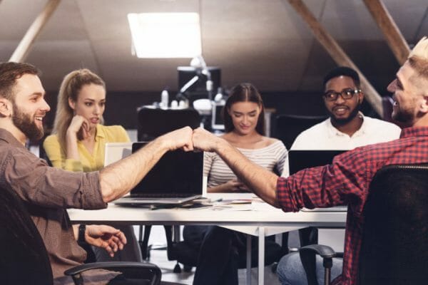 good job. friendly colleagues bumping fists at workplace